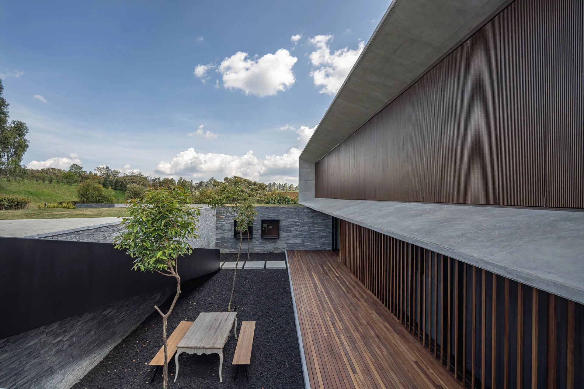Interior de la zona social con chimenea de concreto y techos altos de madera en la casa.